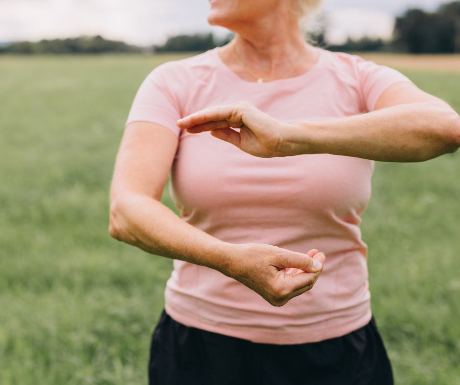 A women in a pink shirt practicing tai chi movements.